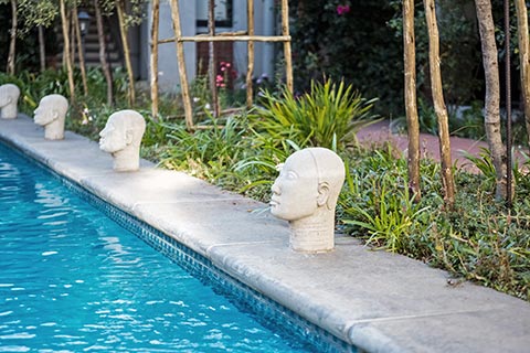 statues of heads along length of pool